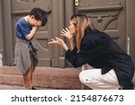Mother scolds her son on the street. A child cries, a woman shakes her finger because of the boy bad behavior, while walking to home. Rule of conduct. Woman sitting, boy cover his face and cry.
