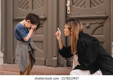 Mother Scolds Her Son On The Street. Child Cries, A Woman Shakes Her Finger Because Of The Boy Bad Behavior, While Walking To Home. Rule Of Conduct. Woman Sitting, Boy Cover His Face And Cry.