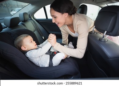 Mother Securing Her Baby In The Car Seat In The Car