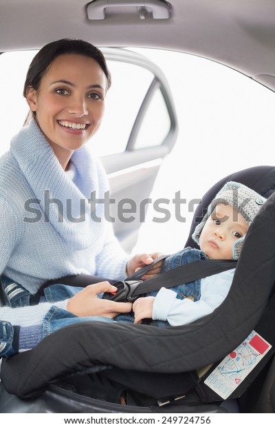 Mother
securing her baby in the car seat in her
car