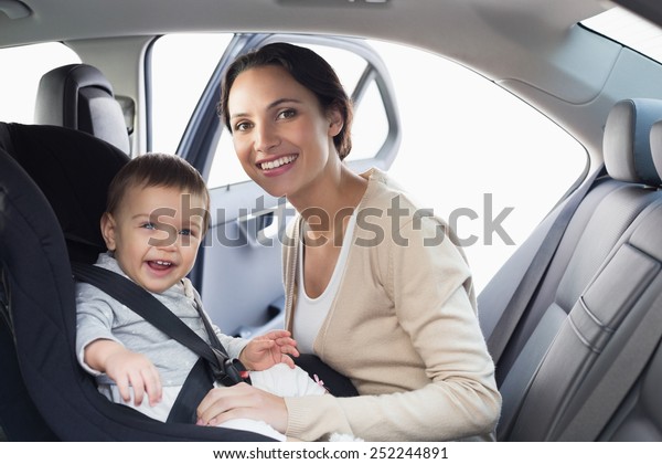 Mother\
securing her baby in the car seat in her\
car