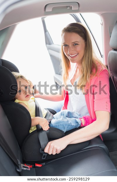 Mother\
securing her baby in the car seat in her\
car