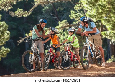 Mother securing the strap of her daughter's helmet and the family is ready for a cycling adventure - Powered by Shutterstock