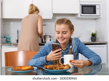 Mother serving breakfast to her teenage daughter in kitchen