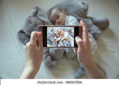 Mother shootin her sleeping newborn baby by smartphone - Powered by Shutterstock