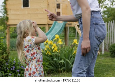 Mother Is Shouting At Her Daughter In Public Park. Upset Little Girl Is Crying In Front Of Her Mother.