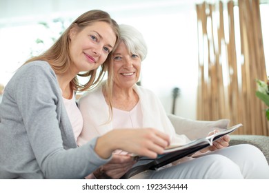 Mother Showing Daughter Photos In Album At Home