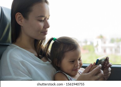 Mother Showing Her Child Educational Videos On A Cell Phone, While Traveling On A Train/bus. 