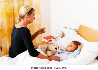 A Mother And Sick Child In Bed. Flu. Childhood Diseases.