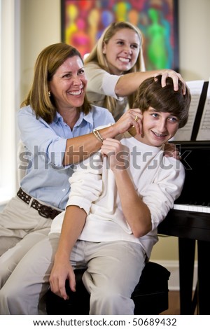 Mother and sister having fun teasing teenage boy at home