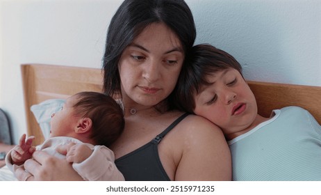 Mother sits with her baby and older child showcasing a serene and intimate family moment The baby sleeps peacefully in her arms while the older sibling rests against her reflecting familial love and - Powered by Shutterstock