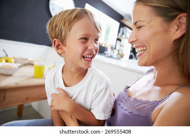 Mother Sitting With Laughing Son At Breakfast Table