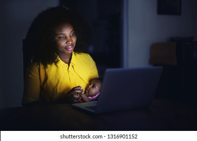 Mother Sitting At Night With The Baby In Front Of The Laptop