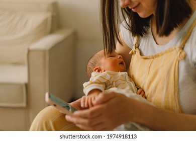 Mother sitting on bed and typing on the cellphone while son is napping. Focus on baby - Powered by Shutterstock