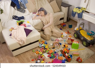 Mother Sitting On The Couch. Mom Tired To Tidy Up The House. Child Scattered Toys. Children's Room. Mess In The House