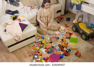 Mother Sitting On The Couch. Mom Tired To Tidy Up The House. Child Scattered Toys. Children's Room. Mess In The House