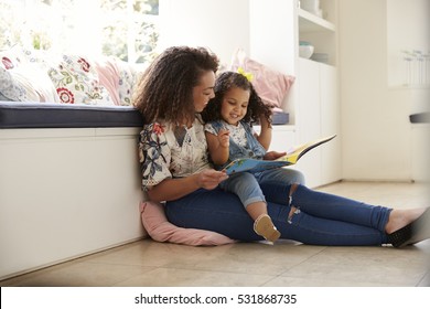 Mother sitting on the floor reading a book with her daughter - Powered by Shutterstock