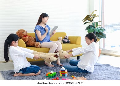 Mother Sitting On Sofa And Surfing Internet, Mom Online Working By Using Tablet Or Social Addiction While Her Kid Daughter Snatching Toys, Mom Not Paying Attention To Children, Sister Quarrel Fight.