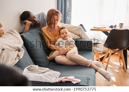 Mother sitting at the sofa with her little newborn baby while spending time together