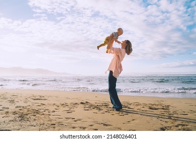 Mother with small child playing and having fun together on beach ocean. Happy family outdoors. Mom and baby at summer on nature. Positive human emotions and feelings. Family holiday on sea coast.
