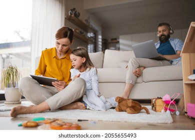 Mother With Small Daughter Using Tablet Indoors At Home, Everyday Life And Home Office With Child Concept.