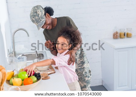 Mother soldier and african american child cooking together