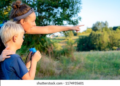 Mother And Son Are Birdwatching While Hiking In Countryside.