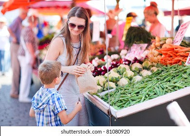 Mother and son buying green peas at market