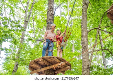 Mother And Son Climbing In Extreme Road Trolley Zipline In Forest On Carabiner Safety Link On Tree To Tree Top Rope Adventure Park. Family Weekend Children Kids Activities Concept