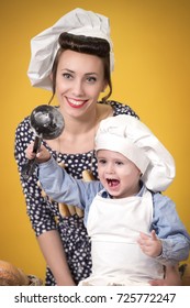 Mother And Son In The Costume Of The Chefs Playing With Flour On Yellow Isolated Background