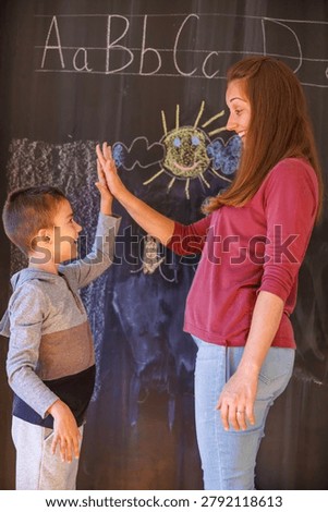 Mother and son doing high-five in front of chalkboard after finishing homework and studying for school