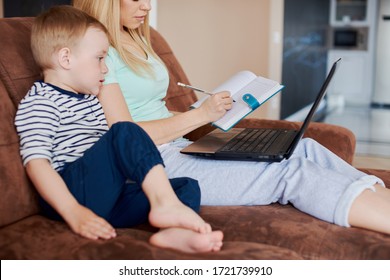 Mother and son drawing in notepad while using laptop