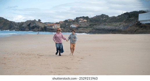 A mother and son enjoy a carefree run on a winter beach - Powered by Shutterstock