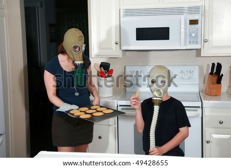 a mother and son enjoy peanut butter cookies in their kitchen while wearing gas masks in a post nuclear winter future