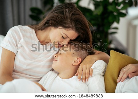 Mother and son enjoying in bed. Happy woman with son relaxing in bed.