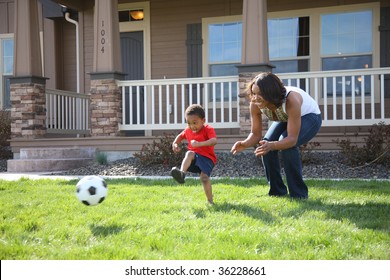 Mother And Son In Front Yard Playing With Soccer Ball