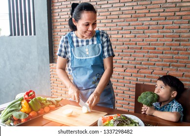 Mother and son are happy to prepare food, cook together in the kitchen. - Shutterstock ID 1337298482
