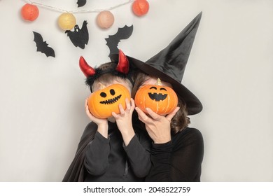 Mother And Son Have Fun Celebrating Halloween In A Witch And Devil Costume. Family Celebration.