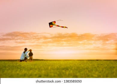Mother and son having fun flying a kite at sunset, outdoor summer family lifestyle,
