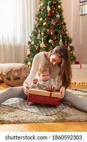 Mother And Son Having Fun At Home On Christmas Morning, Sitting By Nicely Decorated Christmas Tree, Opening Presents And Playing