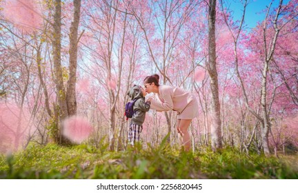 Mother and son holding hands and kissing each other in the forest park. romantic emotion moment. Pink Cherry Sakura Blossom in Thailand. for valentine's and mother's day concepts. family travel. - Powered by Shutterstock