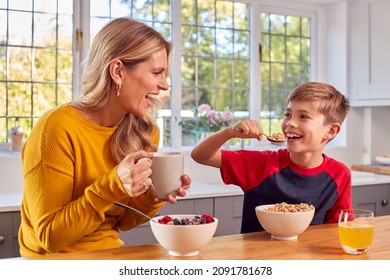 Mother And Son At Home Eating Breakfast Cereal At Kitchen Counter Together