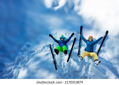 Mother And A Son Lay In The Snow With Ski Lifting Dangle Legs, View From Above Waving Hands Enjoying Winter Vacation