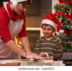 Mother And Son Making Christmas Cake, Son Watching Mum's Hand, Smiling.?