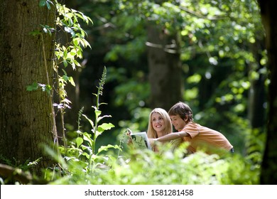 Mother And Son With Nature Guide Book In Forest