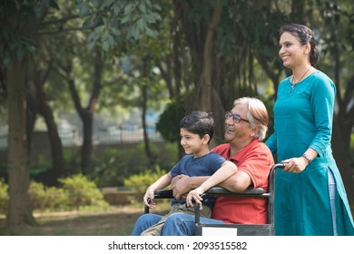 Mother And Son With Old Man In Wheelchair At Park
