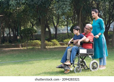 Mother And Son With Old Man In Wheelchair At Park
