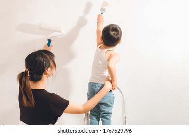 Mother And Son Painting The Wall Together. Mom And Child Fun Times