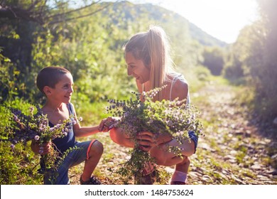 Mutter und Sohn, die Blumen/Kräuter in der Natur pflücken.