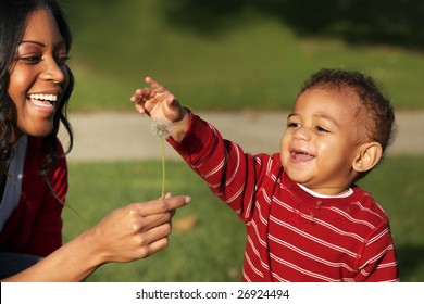 Mother and son playing with a dandelion in the park [16 months]